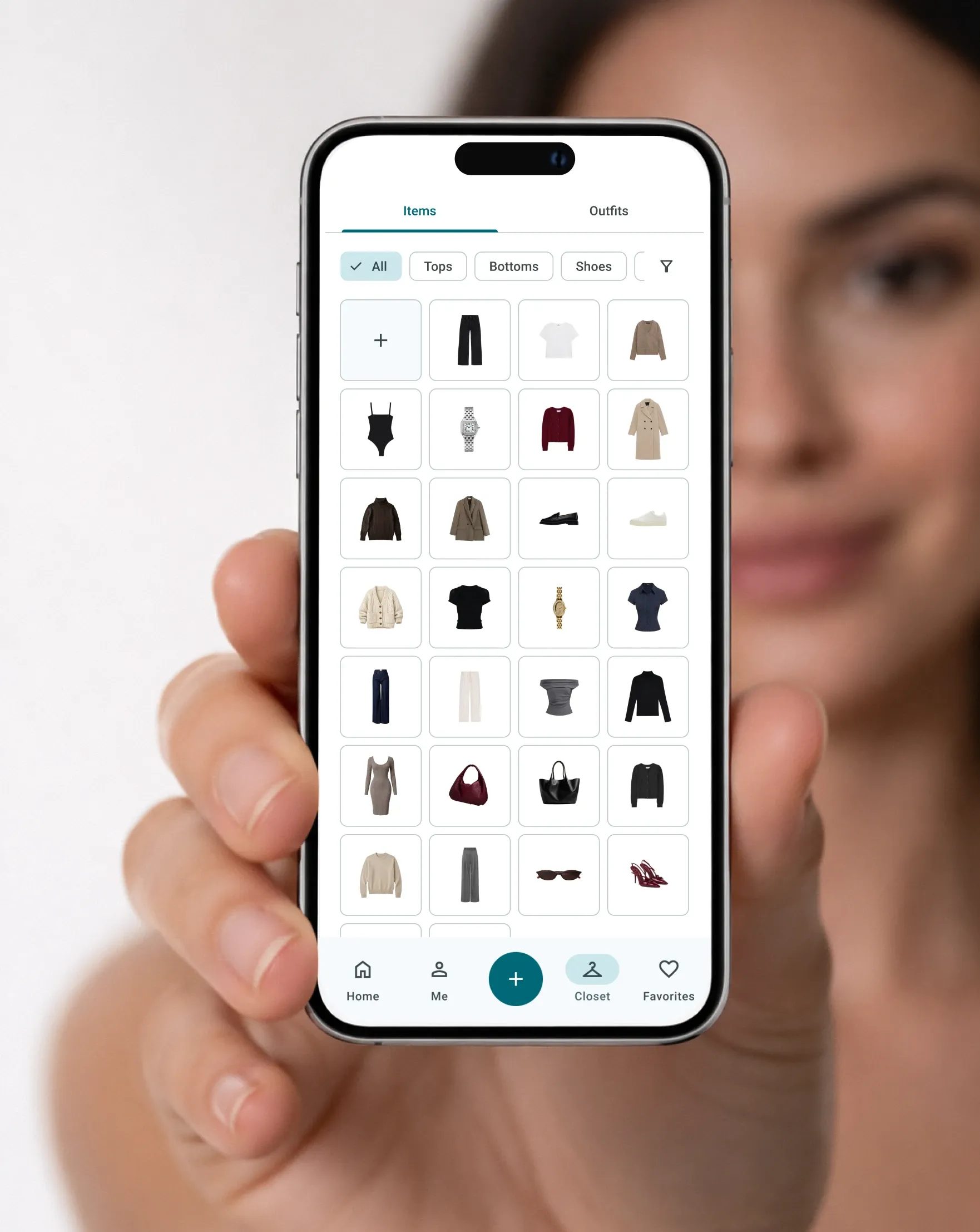 Hand holding a phone with the DrobeMe digital closet open