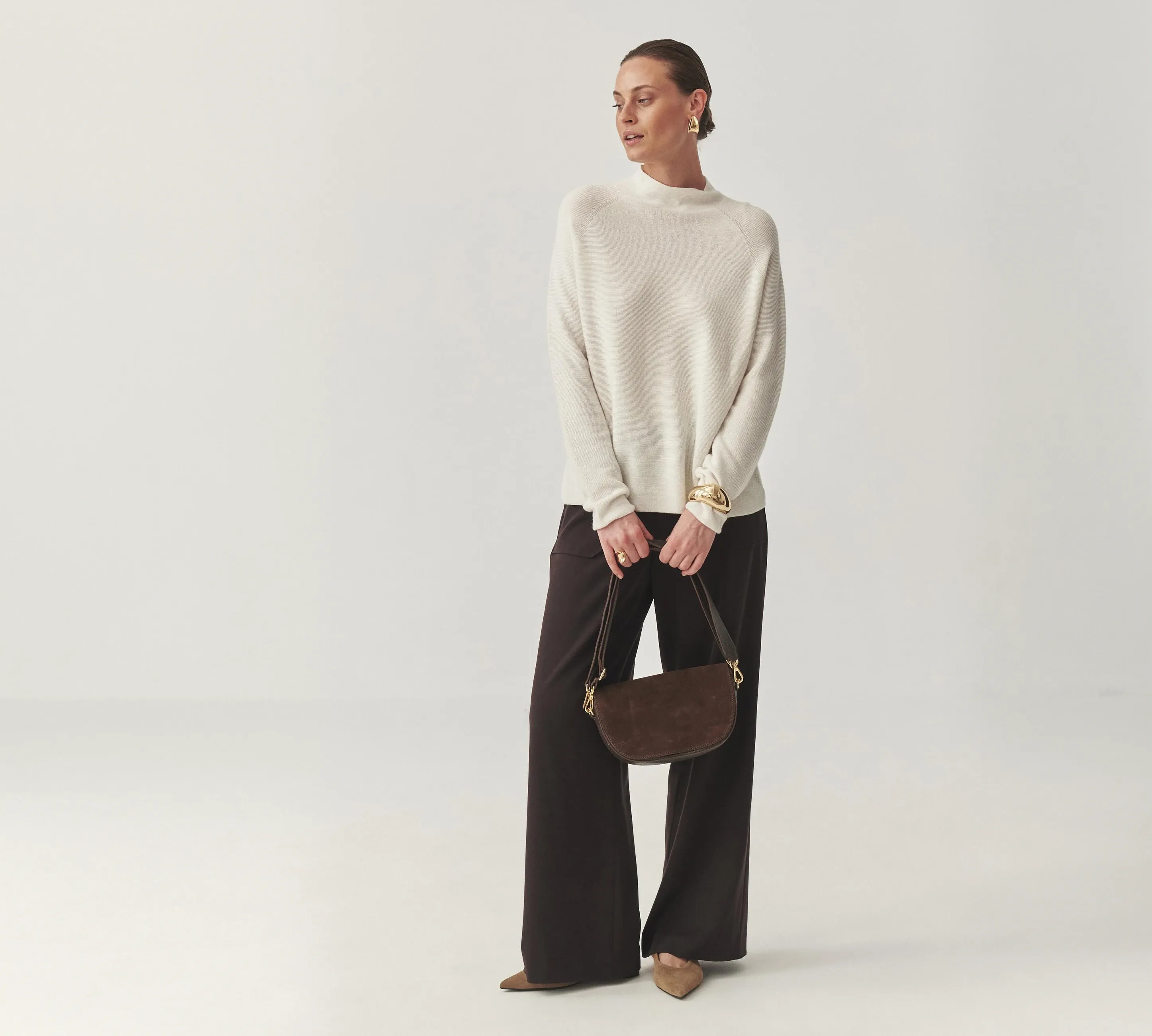 Woman in a cream knit sweater, styled from a curated wardrobe